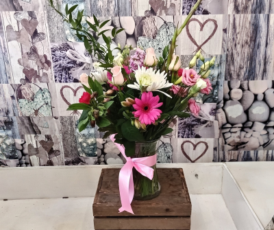 Blush and Bloom - A beautifully arranged vase display featuring a delightful mix of soft blush, vibrant pink, and crisp white seasonal blooms, complemented by fresh greenery and elegant textures. Finished with a satin ribbon