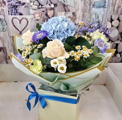 Bluebell and Bramble - A beautifully handcrafted arrangement featuring soft blue, ivory, and delicate pastel tones, complemented by fresh greenery and charming seasonal accents. Presented in a stylish keepsake gift box with premium wrapping and a satin ribbon