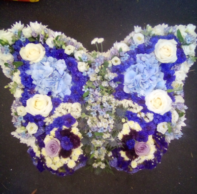 Butterfly - A beautifully shaped butterfly tribute designed in calming shades of blue, lilac and white. Richly textured and thoughtfully detailed, this meaningful farewell piece symbolises peace, freedom and treasured memories, creating a heartfelt tribute to someone deeply loved and forever remembered.