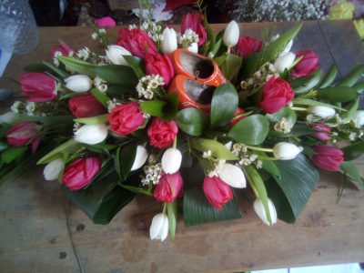 Cherished Memories - A striking and deeply personal tribute designed in vibrant red and crisp white tones, beautifully arranged with rich greenery and a treasured keepsake at its heart. Full of warmth, character and meaning, this bespoke arrangement offers a unique way to celebrate a cherished life and the memories that made them special.